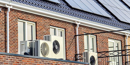 air source heat pump unit installed outdoors at a top floor apartment with solar panels on the roof